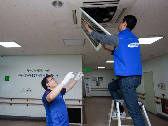 17일 삼성전자서비스 임직원들이 수원장애인종합복지관에서  냉난방시스템에어컨을 수리하고 있다.  <삼성전자서비스 제공>